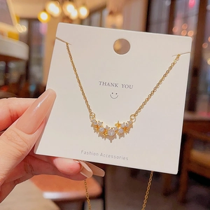 Close-up of sparkling star pendant necklace with gold chain held by hand on card