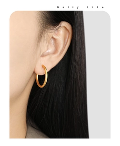 Close-up of minimalist 30mm golden titanium hoop earring worn on an earlobe