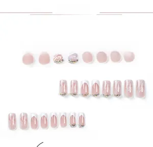 Macro detail of nude pink press-on nails with white French tips and rhinestone accents
