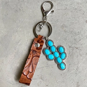 Detail of vintage embossed brown leather keychain with turquoise cactus pendant and silver hook