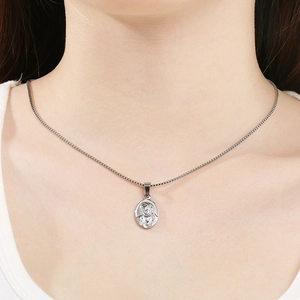 Detail of silver oval portrait pendant on box chain worn by a fashion model