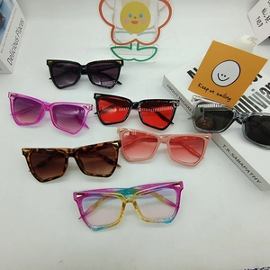 Flat lay of colorful oversized cat-eye sunglasses with gold rivet details on white surface