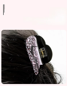 Detail showing the pink leopard print hair claw clip with a strong metal spring on black hair