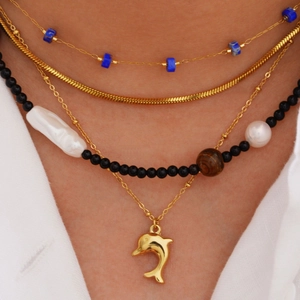Detail of layered gold stainless steel necklace with ocean charms and baroque pearls