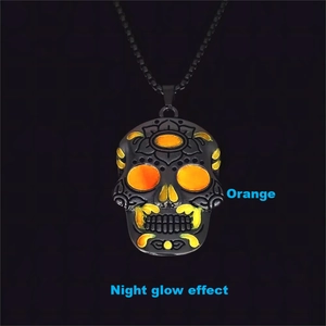 Detailed view of black metal skull pendant featuring ornate carving and orange night glow effect