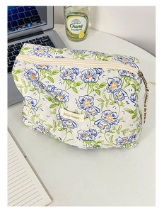 Dettaglio della borsa da trucco trapuntata bianca a fiori blu su una scrivania da ufficio