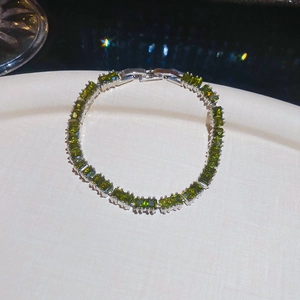 Macro detail of emerald green rectangular stones set in silver 18k plated metal bracelet