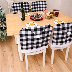 Gros plan de housses de chaise de Noël à carreaux noirs et blancs avec pompons blancs