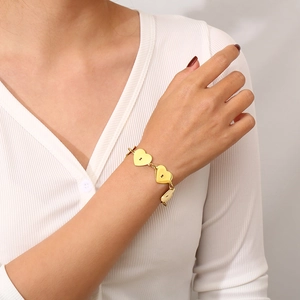 Détail du bracelet à maillons en cœur plaqué or 18 carats porté au poignet, fini poli