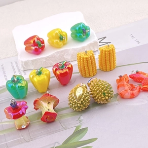 Macro shot of realistic resin food charms like corn, chili, and shrimp with metal rings