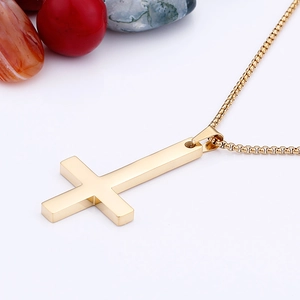 Close-up of golden stainless steel cross pendant necklace with a polished box chain