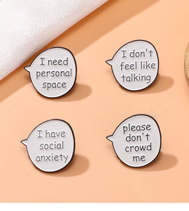 Set of four white speech bubble metal pins with social boundary text on orange surface