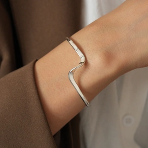 Close-up of polished silver wavy geometric cuff bracelet on a model wrist
