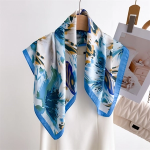Floral print square silk scarf with blue and yellow patterns draped on a wooden hanger
