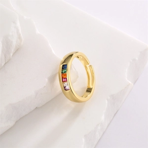 Detail of adjustable gold ring featuring rainbow baguette zircons on a white stone base