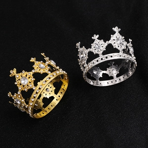 Close-up of mini gold and silver metal cake topper crowns with sparkling rhinestones