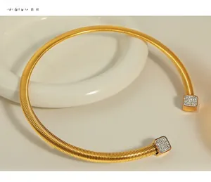 Détail d'un tour de cou doré avec texture en spirale et embouts carrés en strass