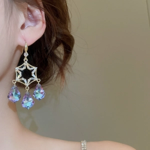 Macro view of gold star earrings with sparkling crystal droplets and tassels