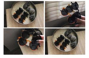 Detailed view of vintage tortoiseshell and black round sunglasses on a wooden tray