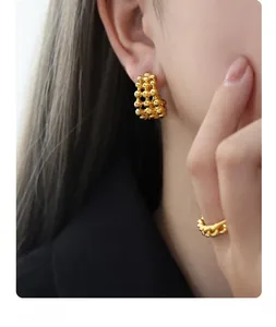 Detail of gold C-shaped beaded mesh earrings and matching ring on model profile