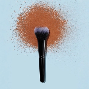 Black flame-shaped makeup brush with purple tips for powder and blush on blue background