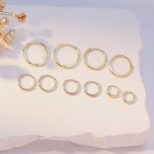 Various sizes of gold S925 sterling silver hoop earrings shown on a marble surface