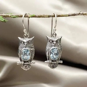 Vintage silver owl drop earrings with sky blue topaz stones on a natural branch