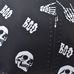Detailed macro view of white skull and BOO graphics on black cotton twill baseball cap fabric