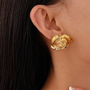 Vue macro de boucles d'oreilles rose dorée avec texture florale 3D métallique