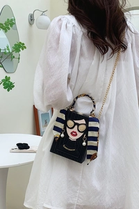 Detail of crossbody box bag featuring girl graffiti pattern and pearl earring accents