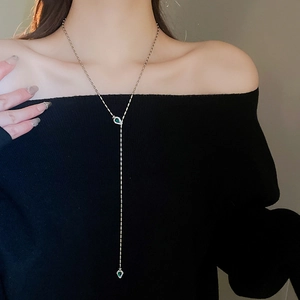 Y-shaped long necklace detail with deep green teardrop pendants and sparkling zircons