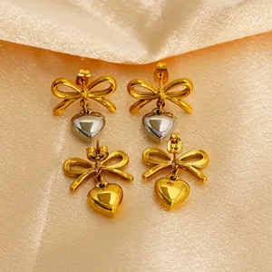 French style 18k gold plated bow and heart stud earrings on silk fabric background