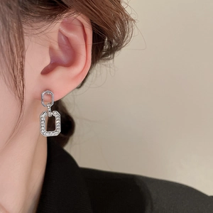 Detail of silver geometric intertwined earrings with crystal pavé on model's ear
