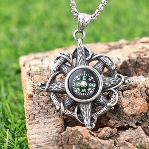 Detailed view of a vintage silver compass necklace pendant placed on a rustic wood piece