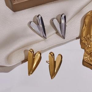 Makro-Detail von polierten herzförmigen Ohrsteckern in Gold und Silber auf Satin