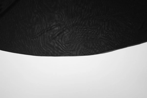 Detail of sheer black mesh fabric showing fine breathable texture and edge finish