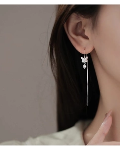 Close-up of s925 silver bow earrings with long tassel chains worn by a model