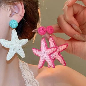 Detailed view of handmade woven raffia starfish drop earrings in pink and white