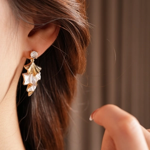 Detail of fan-shaped bicolor leaf earring with zircon stud on model with natural lighting