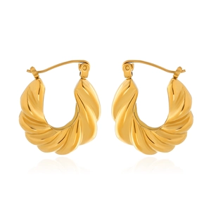 Détail macro des boucles d'oreilles créoles croissant dorées en acier inoxydable torsadé