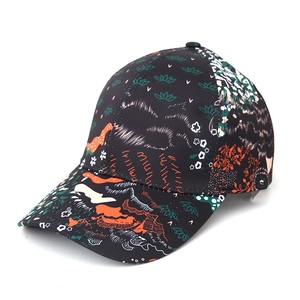 Détail d'une casquette noire avec des motifs floraux artistiques en orange et vert vif
