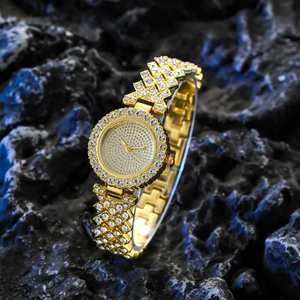 Luxury gold women's quartz watch with full crystal inlay on a dark stone background