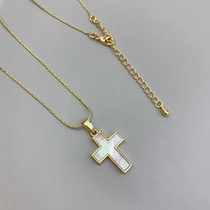 Close-up of gold cross necklace featuring natural white mother of pearl inlay detail
