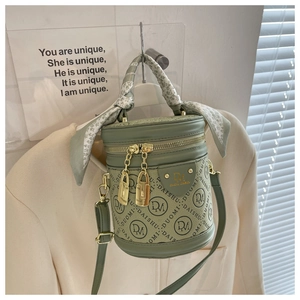 Detail of green cylinder bucket bag with logo print and decorative silk scarf handle