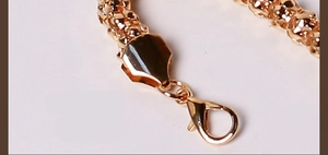 Macro detail of gold metal belt chain featuring texture design and lobster clasp closure