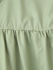 Detailed close-up of sage green woven fabric with vertical pleats and fine stitching