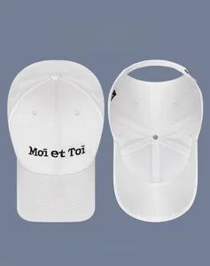 Detail view of cotton white baseball cap with black Moi et Toi embroidery and five color options