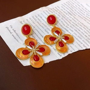Vista macro di orecchini a fiore d'oro vintage con smalto rosso e cristalli