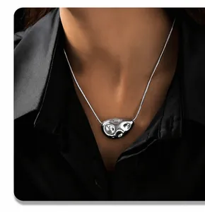 Close-up of a silver liquid metal lava pendant with a sleek snake chain on a model