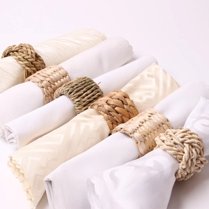 Close-up of assorted natural woven bamboo and grass napkin rings on fabric linens